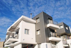 a tall white building with balconies and a blue sky at Agnanti Apartments in Argaka