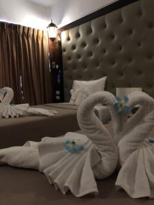 2 serviettes pliées en cygne sur un lit dans une chambre d'hôtel dans l'établissement SUDYOD HOTEL, à Ban Bang Bamru