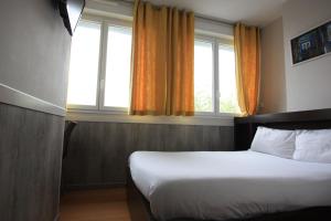 a hotel room with a bed and two windows at Hotel De La Rade in Brest