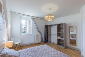 a bedroom with white walls and a bed and a window at Le Maransin in Lourdes