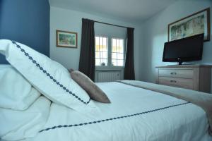 a bedroom with a white bed with pillows and a television at Cabopino Apartament, Marbella´s Beach in Marbella