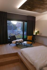 een slaapkamer met een bed, een bank en een raam bij Margaretha's Room in Mechelen