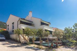 a white house with trees in front of it at Apartments DDD in Baška