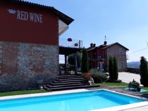 a swimming pool in front of a building with a red wine building at Red Wine Camere in La Morra