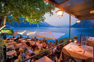 a restaurant with tables and white umbrellas and a lake at Apartment Bella Vista In Mezzegra with POOL sleeps 6- by Italian Apartments in Mezzegra