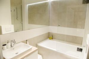uma casa de banho branca com um lavatório e um espelho em ULMA apartment em Wieliczka