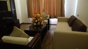 a living room with two couches and a vase of flowers at The Legend in Allahābād
