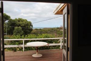 balcón con mesa y vistas al océano en Brandis Beach House en Guilderton