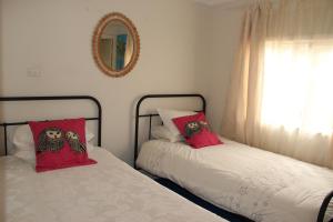 1 dormitorio con 2 camas con almohadas rojas y espejo en Brandis Beach House en Guilderton