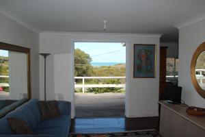 a living room with a blue couch and a sliding glass door at Brandis Beach House in Guilderton