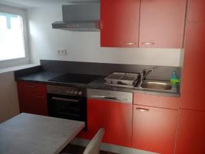 een keuken met rode kasten en een wastafel bij Bei Dinos in Sarstedt