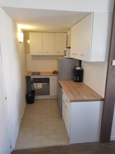 a small kitchen with white cabinets and a refrigerator at 18 rue des petits fossés - 5 in Lourdes