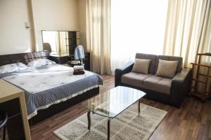 una camera con letto, divano e tavolo in vetro di Apartment on Kunayeva 38 a Shymkent