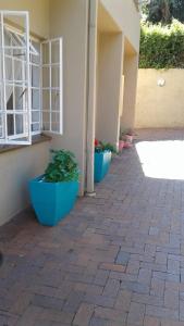 two blue planters sitting outside of a building at The Bedford View Guest House in Germiston