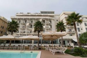 un hotel con sedie e ombrelloni e una piscina di Hotel Abruzzo Marina a Silvi Marina