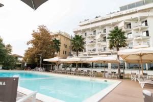 a swimming pool with chairs and umbrellas in front of a hotel at Hotel Abruzzo Marina in Silvi Marina