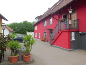 a red building with plants in front of it at Pension Grübel in Lindau +22 photos