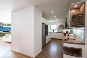 una cocina con armarios blancos y una gran pared blanca en Lake View Apartments, en Keutschach am See