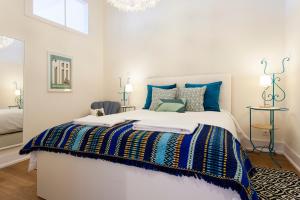 a white bedroom with a large bed with blue pillows at Sao Pedro de Alcantara 63 by Central Hill Apartments in Lisbon