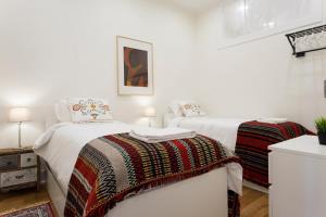 ein weißes Schlafzimmer mit 2 Betten und einem Tisch in der Unterkunft Sao Pedro de Alcantara 63 by Central Hill Apartments in Lissabon