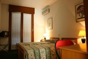 una camera con letto e scrivania con sedia rossa di Hotel Rizzi a Monticello Conte Otto