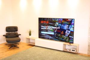 ゲッティンゲンにあるFerienwohnung Müllerの大画面テレビ付きの客室で、黒い椅子が備わります。