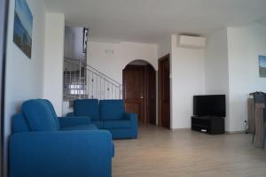 ein Wohnzimmer mit blauen Sofas und einem TV in der Unterkunft Villa Cavour - Doppelhaushälfte in Budoni