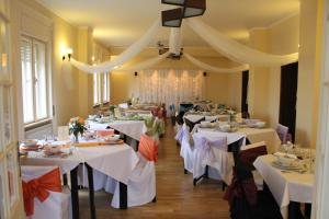 une salle à manger avec des tables et des nappes blanches dans l'établissement Villa Székely, à Leányfalu