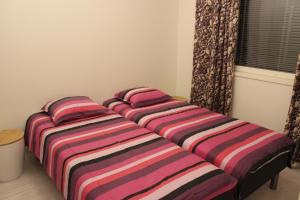 trzy łóżka w pokoju z prześcieradłami w paski w obiekcie Majoituspalvelu Nurmi Apartment Oksapolku 2 A Deluxe Huoneisto 60m3 w mieście Raahe