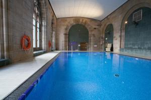 a large swimming pool with blue water in a building at Moat House - Highland Club in Fort Augustus