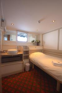 アムステルダムにあるキャプテン アンナのベッド2台、洗面台、鏡が備わる客室です。