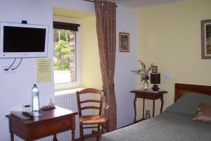 a bedroom with a bed and a television on a wall at Le Moulin du Bignon in Lassy