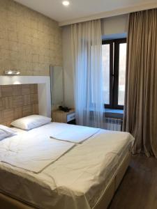 Apartment on Moskovyan 31 في يريفان: غرفة نوم مع سرير أبيض كبير مع نافذة