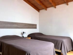 two beds in a room with white walls and wooden ceilings at Patagonien Alquiler Temporario in Puerto Madryn