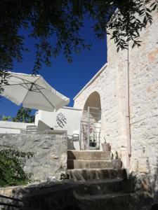 ein weißes Gebäude mit Treppen und einem Regenschirm in der Unterkunft Trullo Nonna Mari in Cisternino