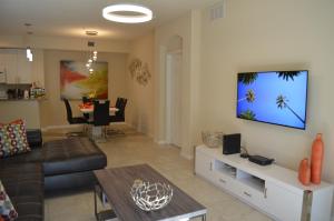 a living room with a couch and a tv on a wall at Fort Myers Luxury Vacation Condo in Fort Myers