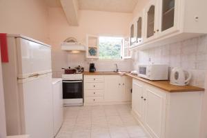 a kitchen with white cabinets and a white refrigerator at Villa Ostria in Lixouri