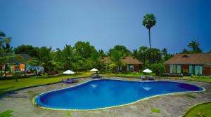 a pool at a resort with chairs and umbrellas at Poovar Island Resort in Pūvār