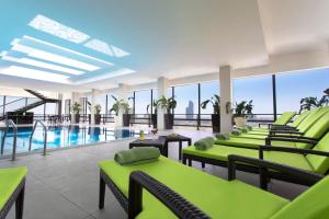 una sala de piscina con sillas verdes y una piscina en Regency Palace Amman, en Amán