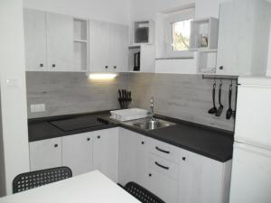 a kitchen with white cabinets and a sink at Apartmani Nena in Povljana