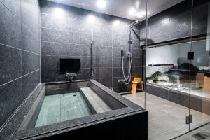 a bathroom with a tub and a glass shower at Kyoto Shijo Takakura Hotel Grandereverie in Kyoto
