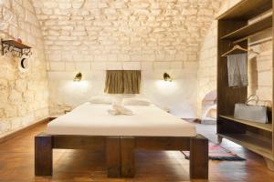 a bedroom with a bed and a stone wall at Fauzi Azar by Abraham in Nazareth