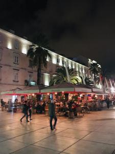 Un gruppo di persone che camminano per una piazza di notte di Villa Urbi et Orbi a Spalato (Split)