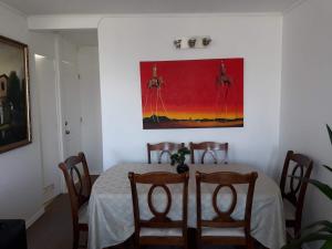 una mesa de comedor con sillas y una pintura en la pared en Apartamento Reinos Francos 414, en La Serena