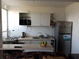 cocina con nevera y mesa con un bol de fruta en Apartamento Reinos Francos 414, en La Serena
