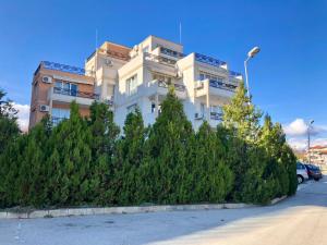 a white building with trees in front of it at Студио Панорама Сънрайз Бяла - кът за отдих и морска почивка in Byala