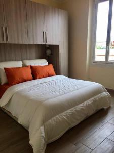 1 dormitorio con 1 cama blanca grande con almohadas de color naranja en Appartamento Quasi Perfetto en Sestri Levante