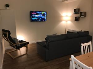 a living room with a couch and a tv on the wall at 2 Lower Kessock Street in Inverness