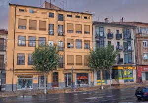 a large yellow building on a street with trees at BUENAVISTA AMBELES in Teruel