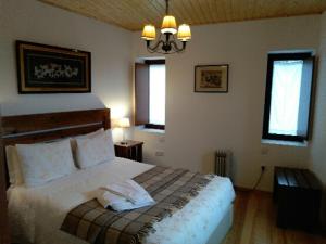 1 dormitorio con 1 cama, 2 ventanas y lámpara de araña en Pátio do Xisto, en Gondramaz